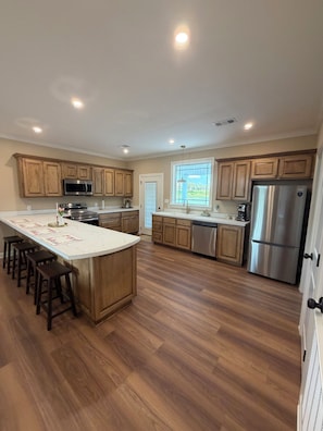 Una cocina moderna con armarios de madera, electrodomésticos de acero inoxidable y una isla central con taburetes de bar.