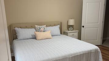 Un dormitorio con una cama, una mesita de noche, una lámpara y una puerta.