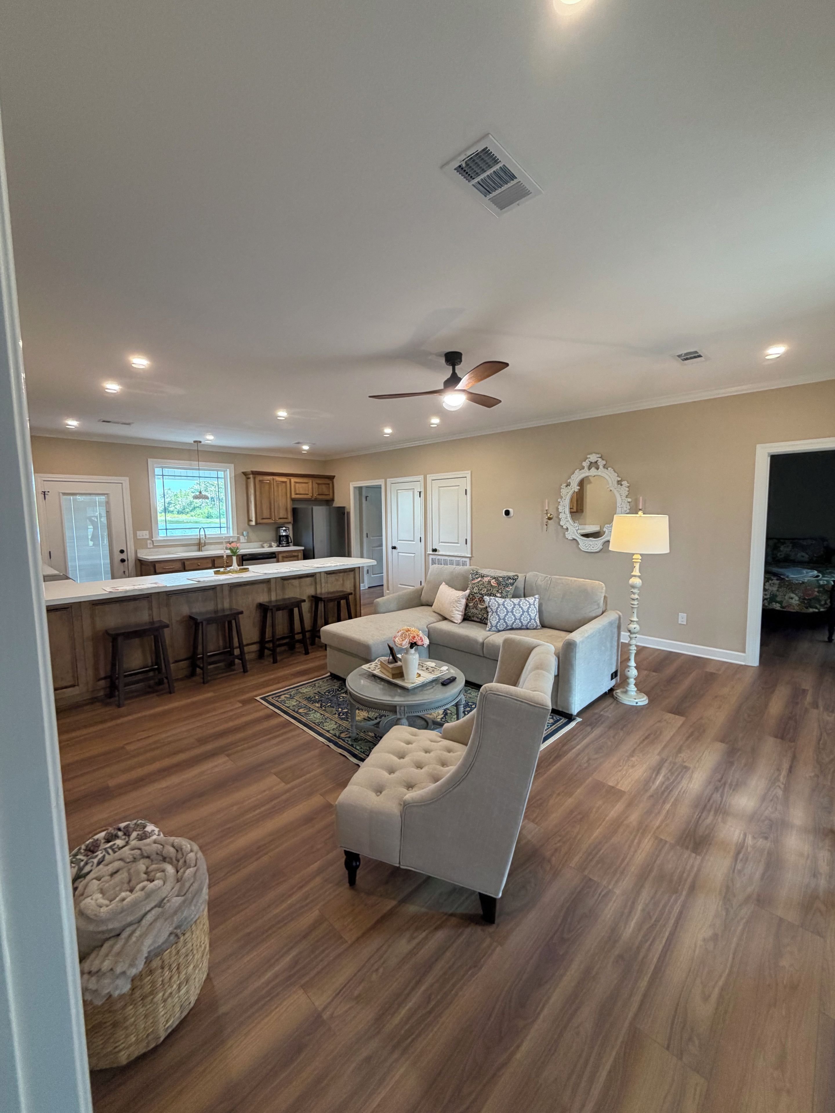 A spacious living area with a sofa, a coffee table, and a dining area with a kitchen in the background.