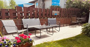 An outdoor seating area with metal chairs and a table, a wooden fence with a sign, and potted flowers. - Location, location! 5 minute walk to main street yet on a cute, quiet street! (Jasper)