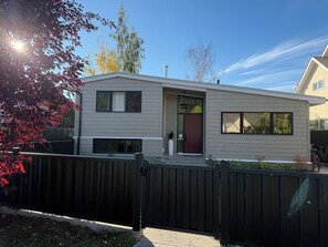 A modern two-story house with a dark brown gate, a red door, and a small porch area. - Location, location! 5 minute walk to main street yet on a cute, quiet street! (Jasper)