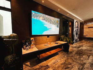 A modern interior with a large flat-screen TV mounted on the wall, a wooden bench, and a marble floor. - Apartment Palace in Poblado (Medellín)