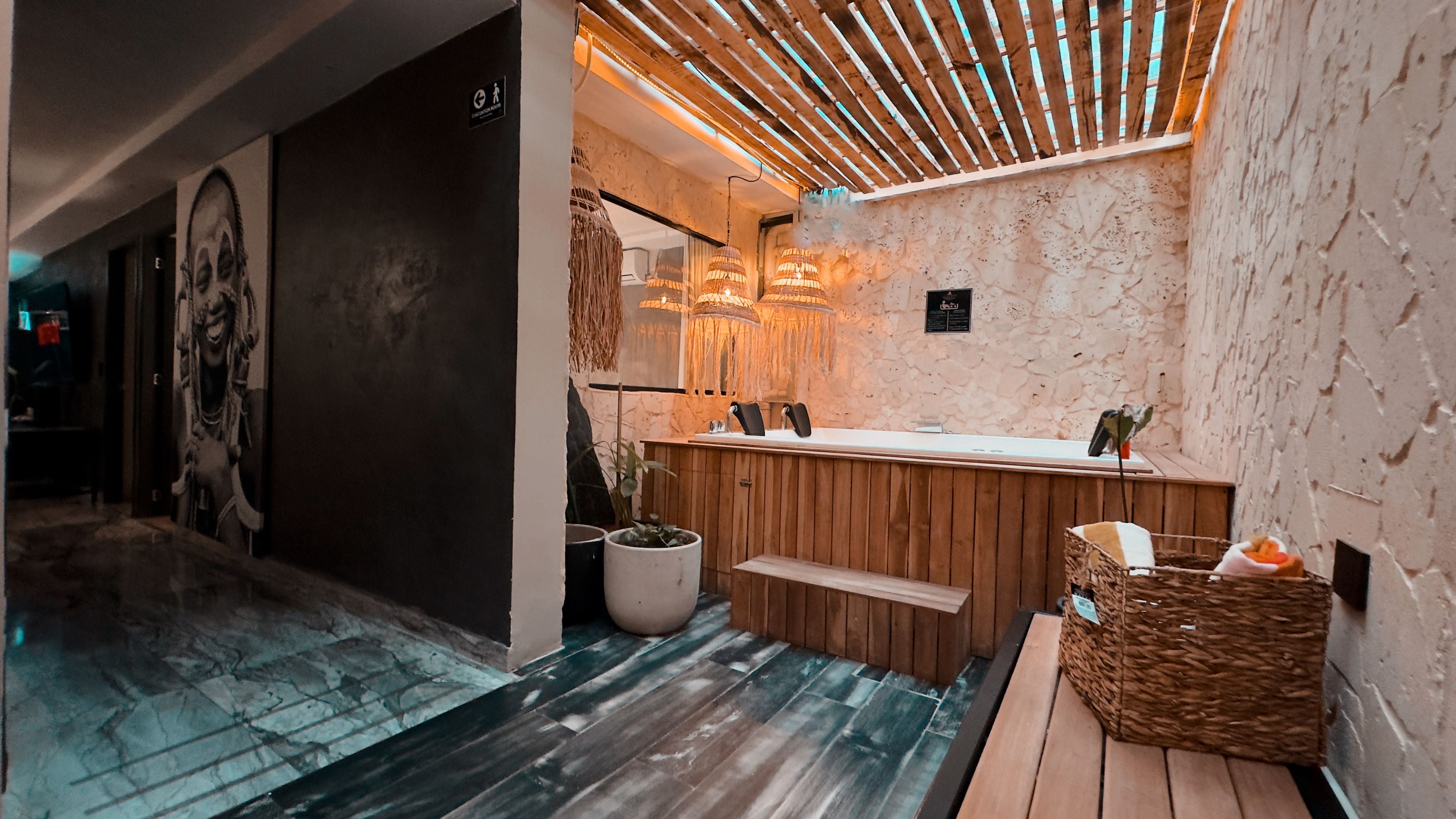 A modern bathroom with a wooden vanity, a large mirror, and a ceiling with wooden slats.