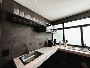 A modern kitchen with a stainless steel sink, a microwave, and a gas stove. - Apartment Palace in Poblado (Medellín)