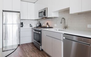 Une cuisine moderne équipée d’appareils électroménagers en acier inoxydable, d’un four à micro-ondes, d’une bouilloire et d’un lave-vaisselle.