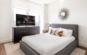 Une chambre à coucher avec un lit, une commode, un téléviseur et un miroir fixé au mur.