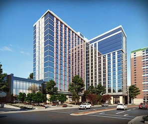 A multi-story hotel with a modern glass facade, a parking lot, and a clear sky. - High-End White Plains 1 Bed with Luxury Amenities (White Plains)