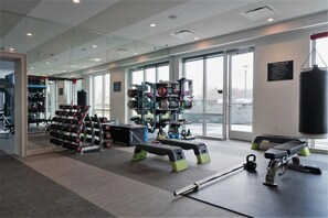 Une salle de sport équipée de divers appareils d’entraînement, notamment des haltères, des kettlebells et un sac de frappe.