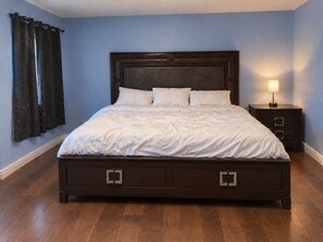 Una camera da letto con un letto grande, una testiera in legno scuro, due comodini e un tavolino da notte con una lampada.