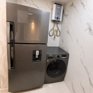 A compact kitchen with a stainless steel refrigerator and a washing machine. - Citrus Cove | Sea Views, Pool & 3BR (Cartagena)