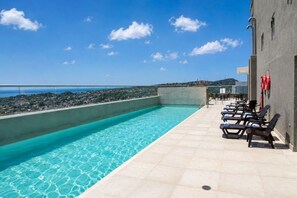 A rooftop pool with clear blue water, a view of the sea, and a row of sun loungers. - Citrus Cove | Sea Views, Pool & 3BR (Cartagena)