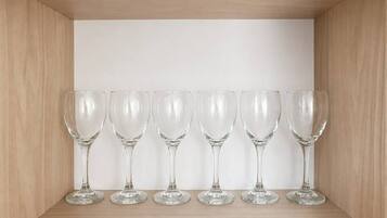A wooden cabinet with a white interior, holding six clear wine glasses.