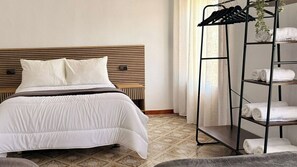 Ein Hotelzimmer mit Bett, Kopfteil, Ablagefläche mit Handtüchern und einem gemusterten Boden.