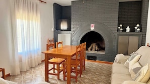 Ein Wohnzimmer mit Kamin, einem Esstisch mit Stühlen und einem Sofa.