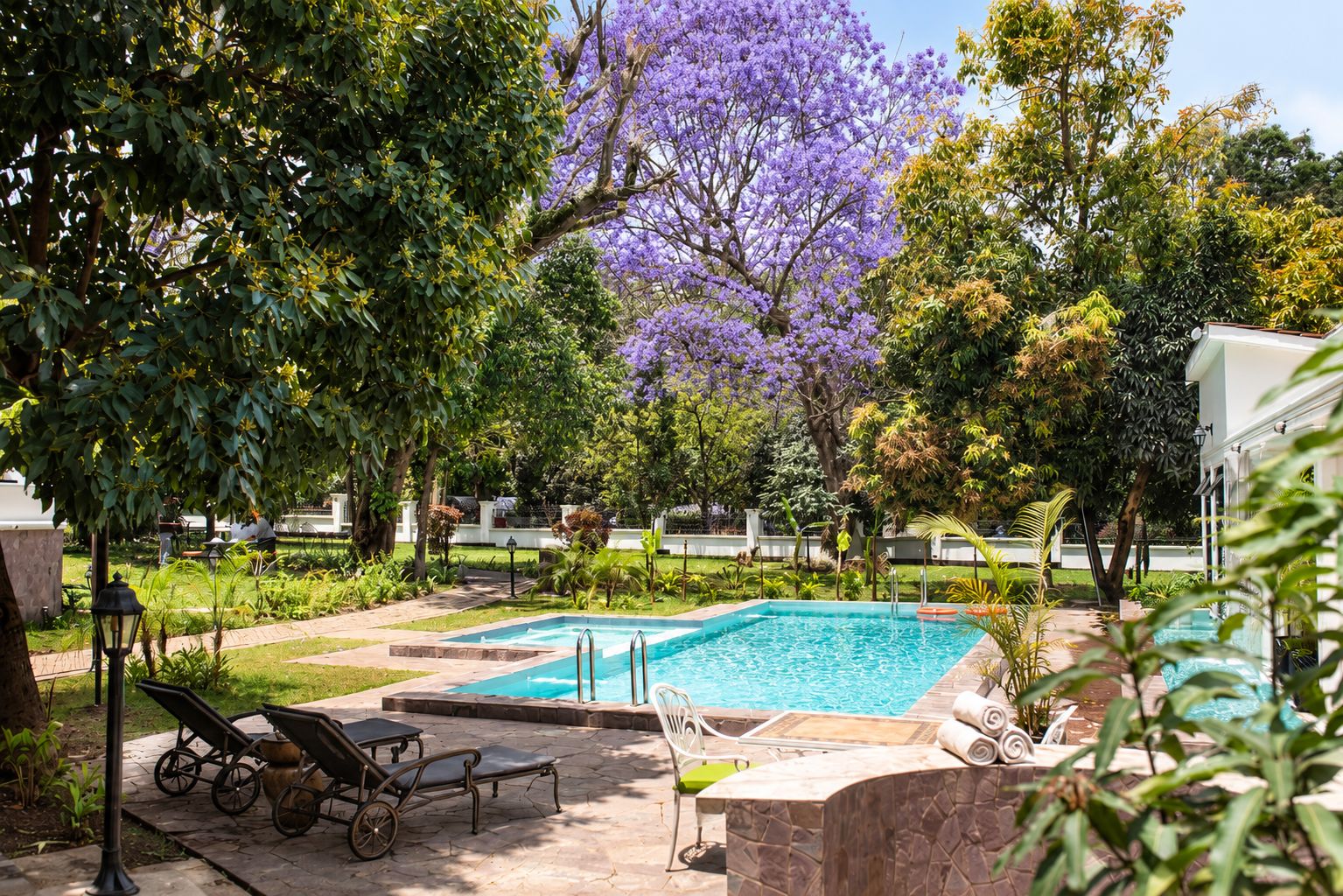 A swimming pool with lounge chairs and a garden area with various plants and trees.