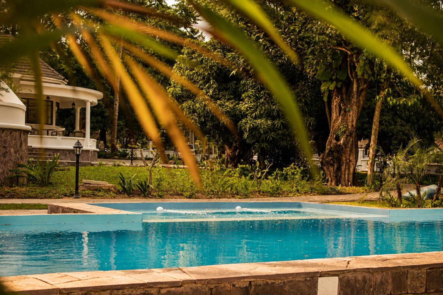 Une piscine agrémentée d’une fontaine, entourée d’une végétation luxuriante et d’un belvédère.