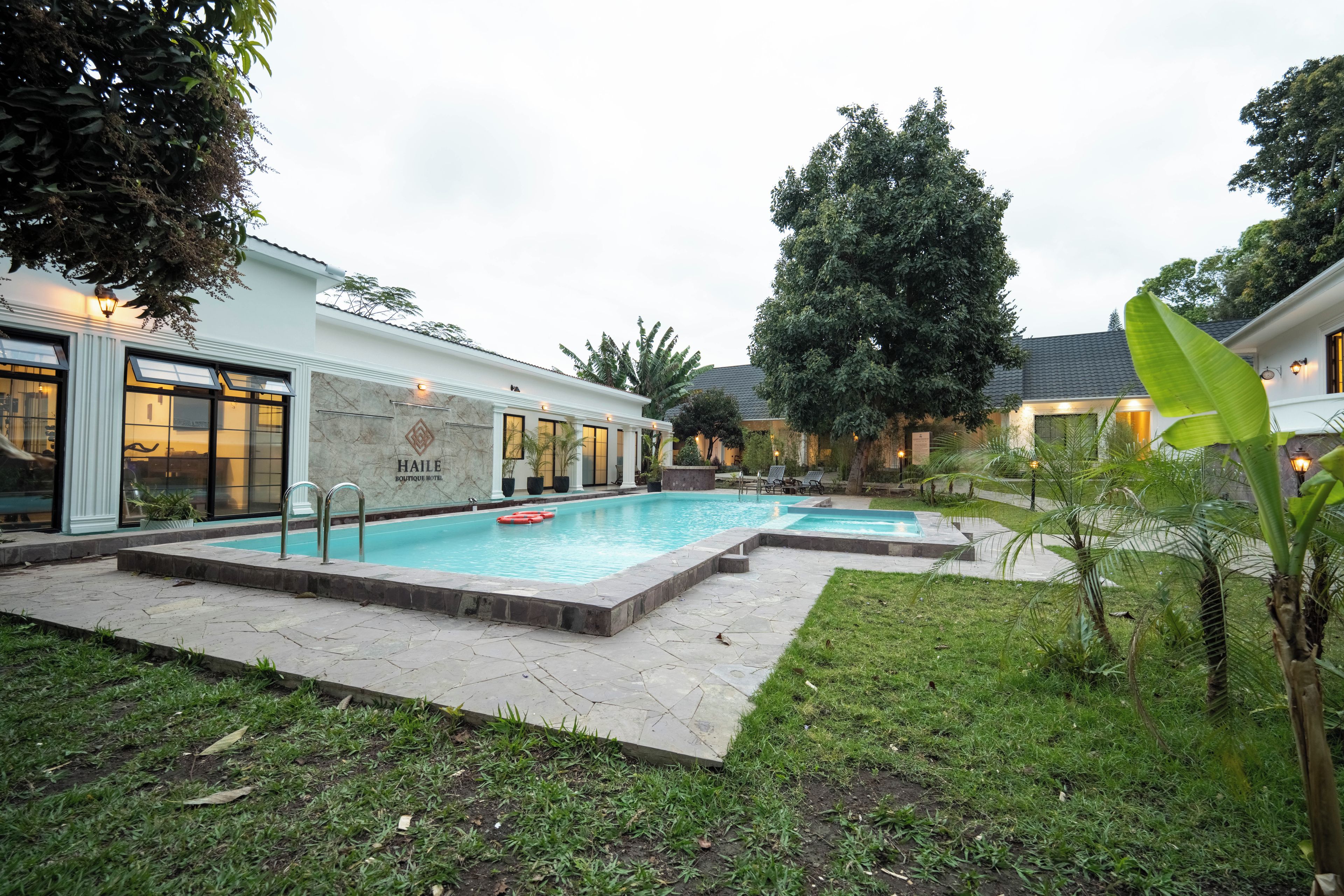 Een hotel met een zwembad, terras en een verzorgde tuin.