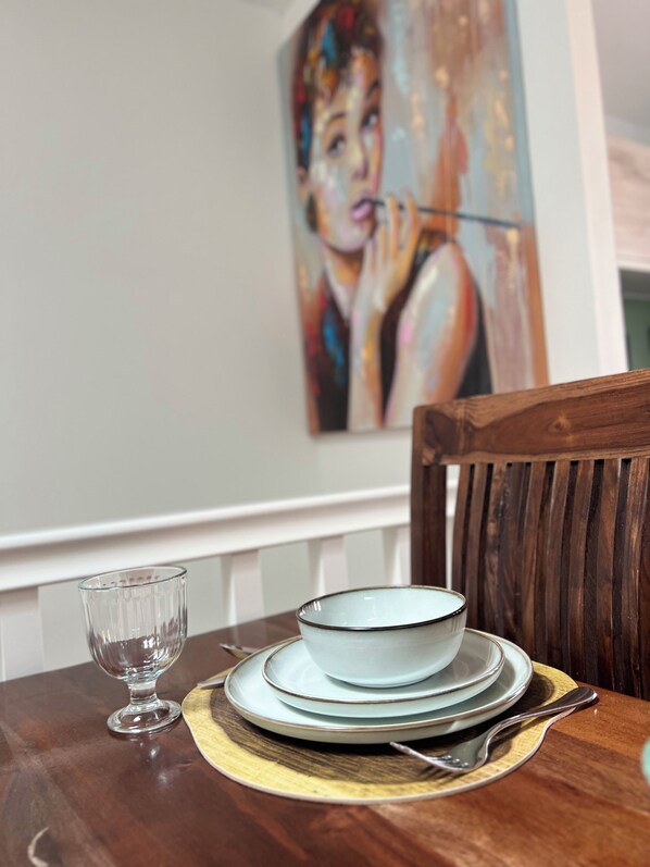 A dining table with a bowl, plates, a glass, and cutlery.