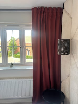Une pièce avec une fenêtre, un radiateur, une petite plante en pot et une table noire.