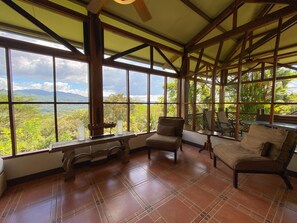 A spacious room with large windows, a wooden ceiling, and a view of a lush landscape. - 3BR Villa  Private Pool by Carara Park (lagunillas)