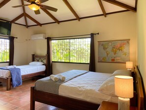 A hotel room with two beds, a ceiling fan, a map on the wall, and a window with bars. - 3BR Villa  Private Pool by Carara Park (lagunillas)