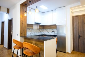 Eine moderne Küche mit Kochinsel, Holzelementen und einem Edelstahl-Kühlschrank.
