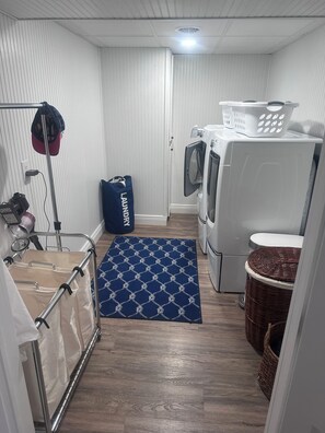 A laundry room with a washing machine, dryer, and a drying rack with a blue mat.