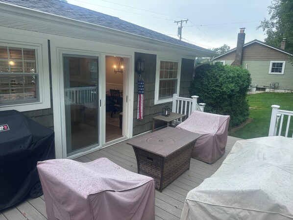 A covered patio with a table and chairs, a barbecue grill, and a view of the house.