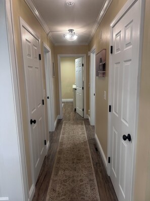 A hallway with white doors, a patterned carpet, and a ceiling light fixture.