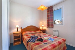 Ein Schlafzimmer mit einem hölzernen Bett, zwei Nachttischlampen, einem Fenster mit Aussicht und einer Heizung.