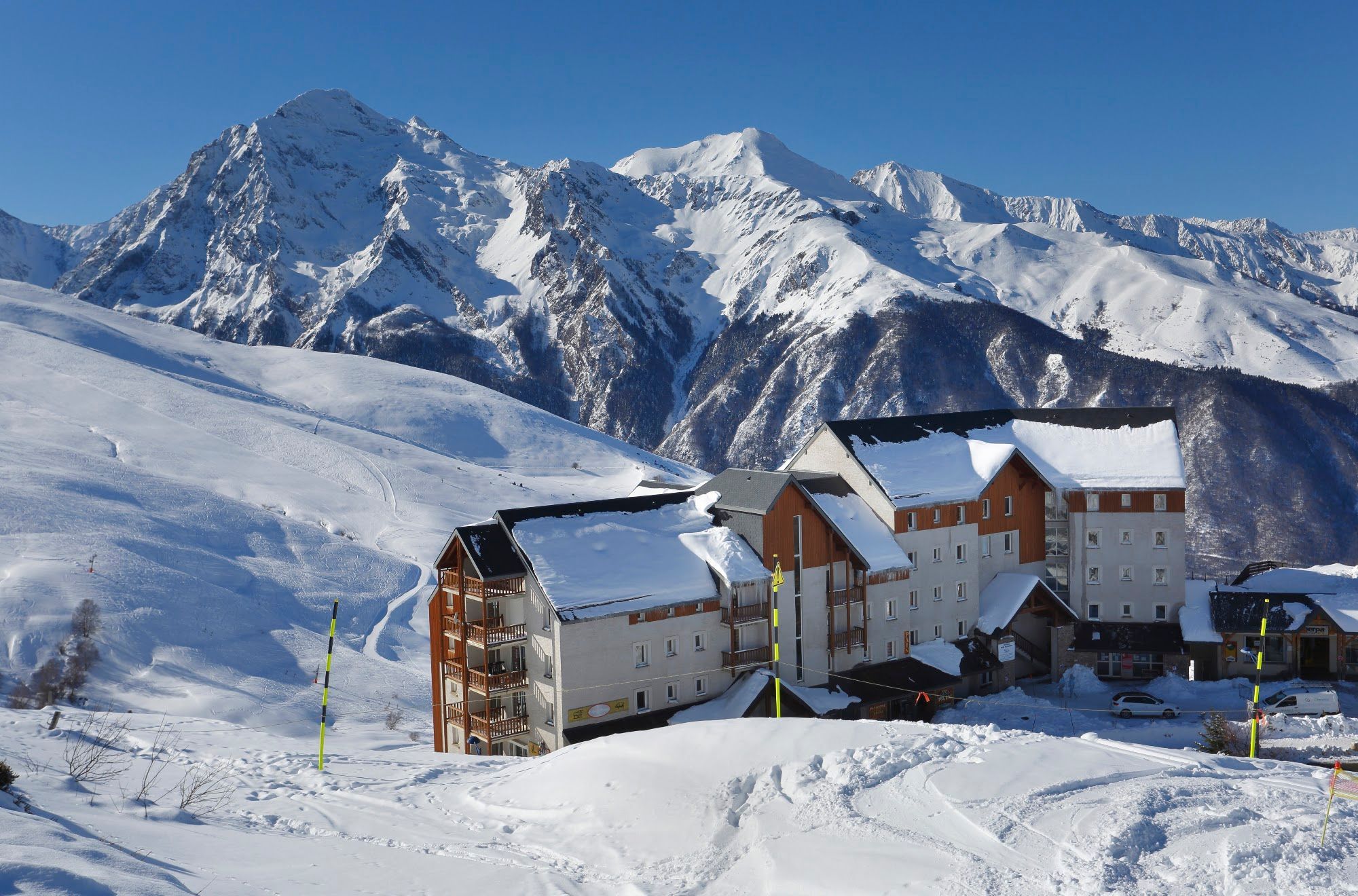 Un complejo turístico en la nieve con edificios de estilo chalete y una pista de esquí.