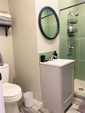 Une salle de bain comprenant des toilettes, un lavabo et un espace douche.