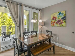 A dining area with a wooden table, chairs, and a pendant light. - Sandestin Condo with Pool, Tram & Resort Perks (Miramar Beach)