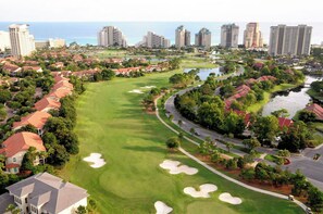 Ein Golfplatz mit Sandbunkern, einem Wassengebiet und umgebenden Wohngebäuden.