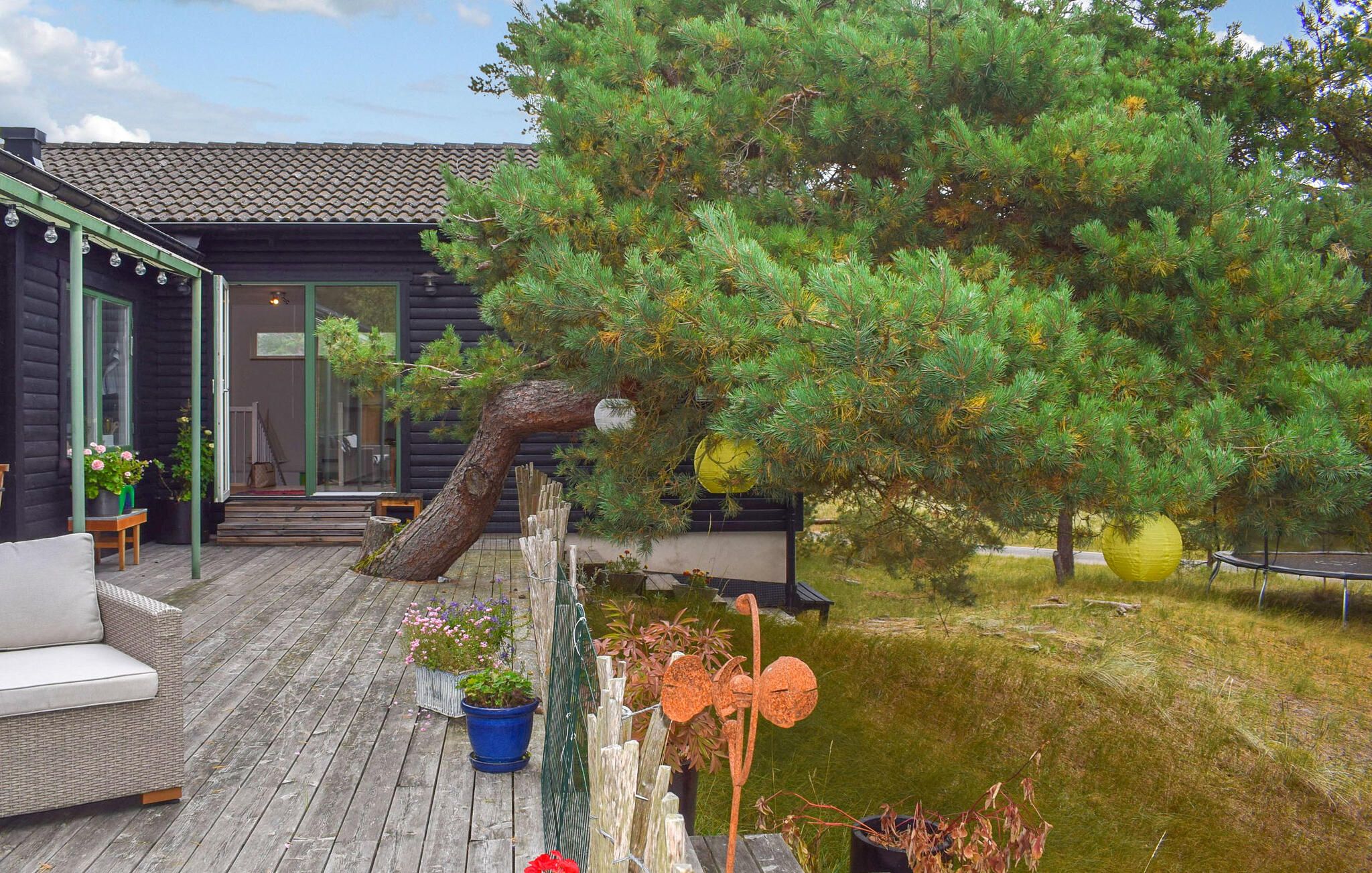 A wooden deck with outdoor seating, a tree, and a small pond.