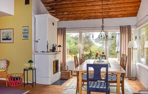 A dining area with a wooden table, chairs, and a view of greenery outside. - Stunning home in Borrby with house a panoramic view (Borrby)