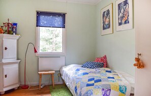 A bedroom with a bed, a window with a curtain, a radiator, a small stool, and a cabinet. - Stunning home in Borrby with house a panoramic view (Borrby)