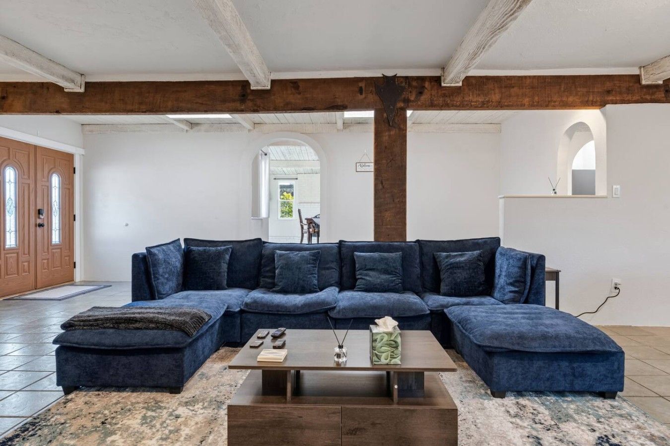 A modern living room with a large sectional sofa, a coffee table, and a fireplace.