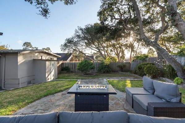 Un jardin avec une terrasse en pierre, du mobilier d’extérieur et un foyer.