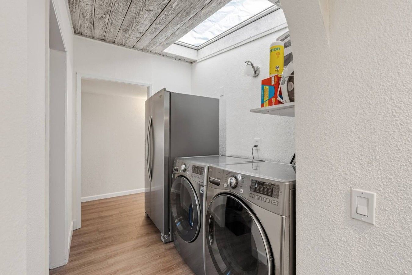 Pequeña área de lavandería con lavadora, secadora y refrigerador.