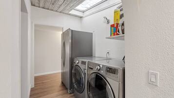 Pequeña área de lavandería con lavadora, secadora y refrigerador.