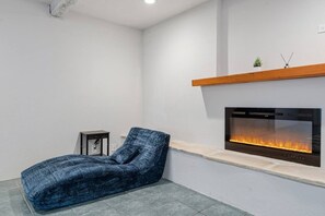 Un salon moderne avec une cheminée intégrée, un fauteuil recouvert de tissu bleu et une petite table.
