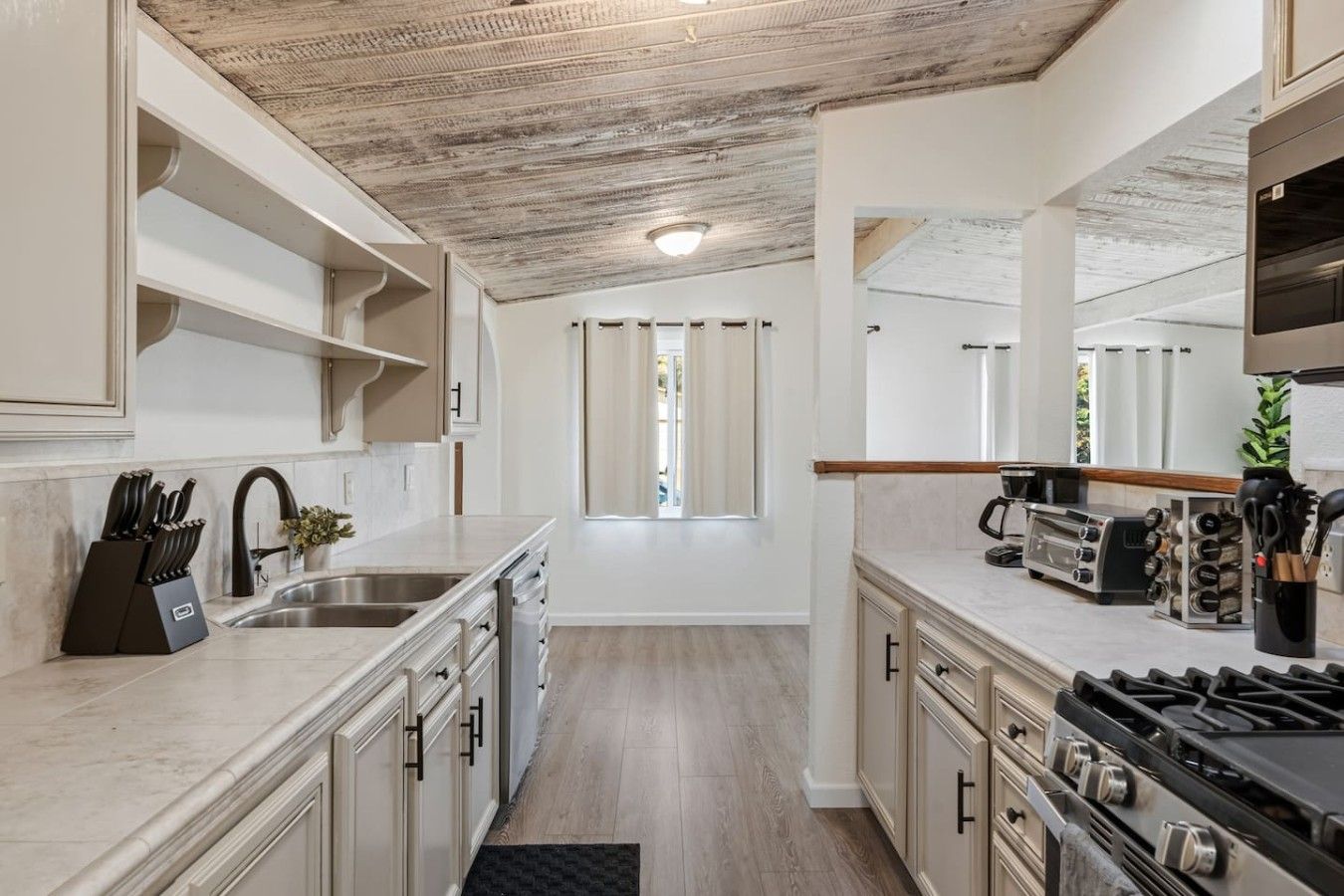 A modern kitchen with a central island, stainless steel appliances, and a view to the outside.