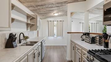 A modern kitchen with a central island, stainless steel appliances, and a view to the outside.