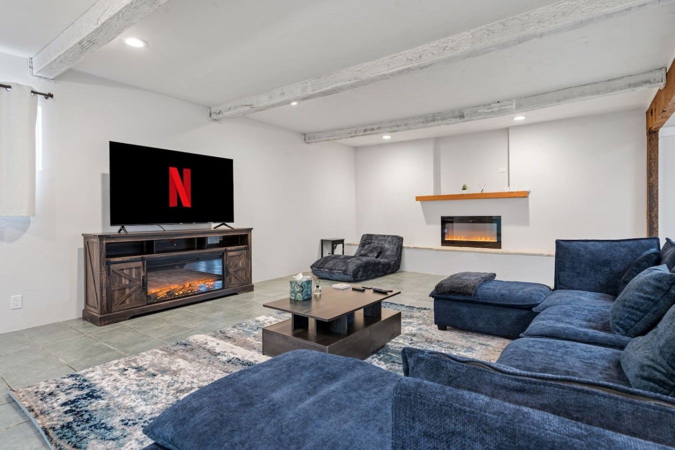 A modern living room with a fireplace, a flat-screen TV, and a comfortable seating area.