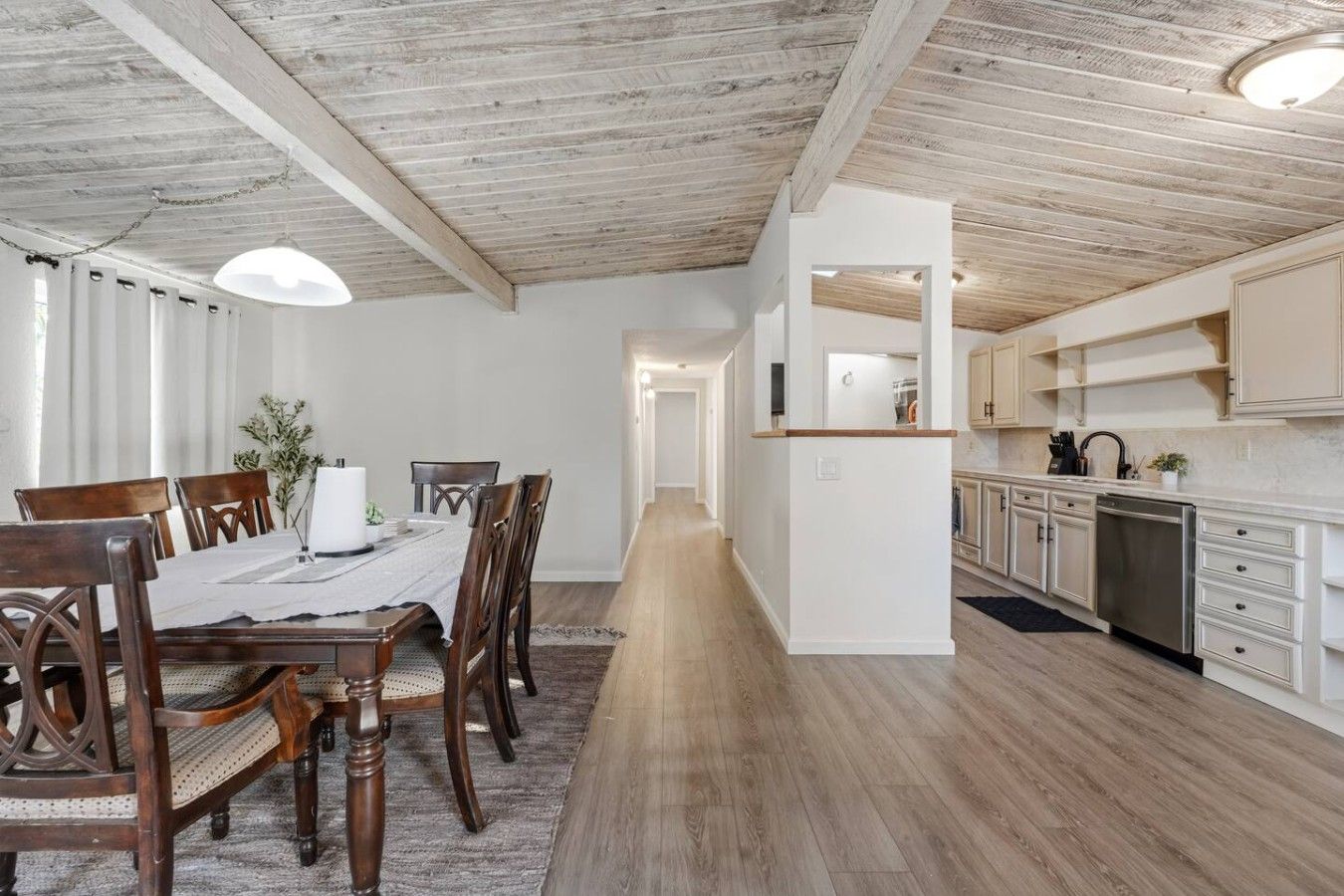 A modern kitchen with white cabinets, a stainless steel dishwasher, and a wooden countertop.