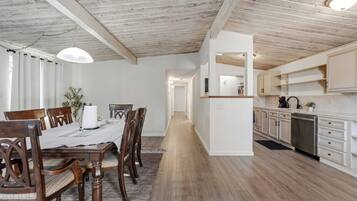 A modern kitchen with white cabinets, a stainless steel dishwasher, and a wooden countertop.
