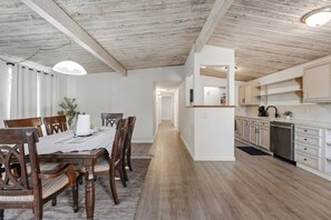 Une cuisine moderne avec des meubles blancs, un lave-vaisselle en acier inoxydable et un plan de travail en bois.