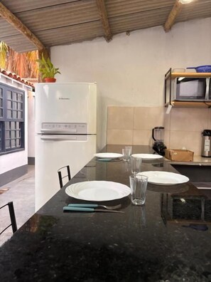 Eine Küche mit schwarzer Arbeitsplatte, weißen Tellern und einem Kühlschrank.
