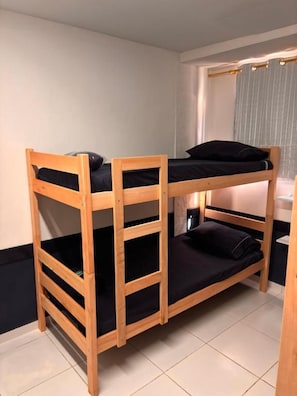 A bunk bed with a wooden frame and black bedding. - Primos 2 Suites & Hostel (Búzios)